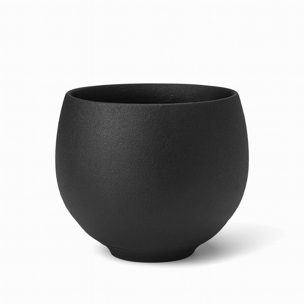 Keramische theekop met bruine en crèmekleurige handgeborstelde texturen op een donker houten oppervlak.