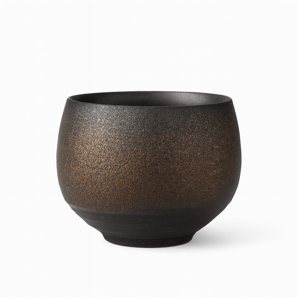 Keramische theekop met bruine en crèmekleurige handgeborstelde texturen op een donker houten oppervlak.